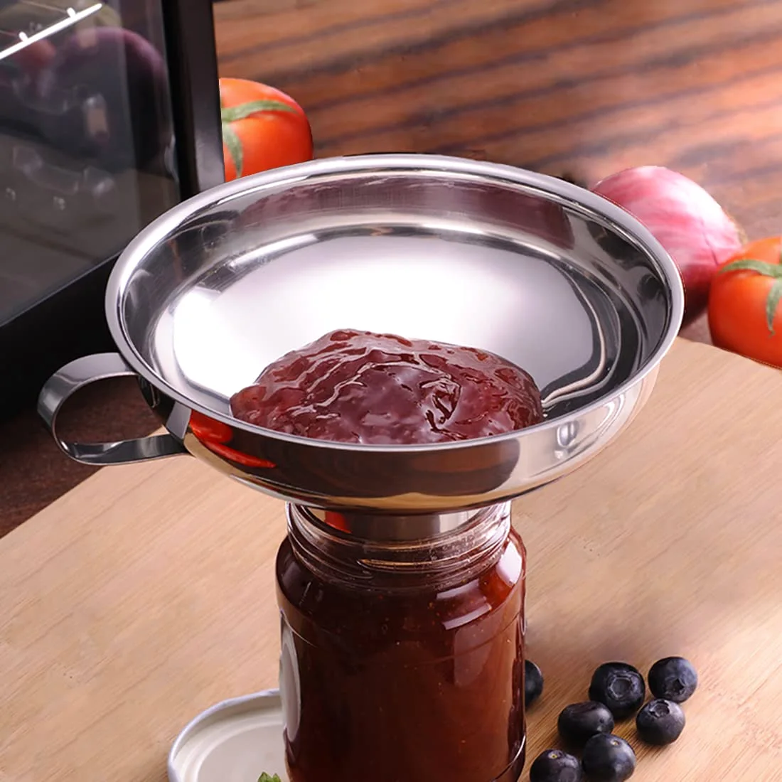 The Delove stainless funnel resting on a jar of jam, with the spout inside the mouth and the rim clear.